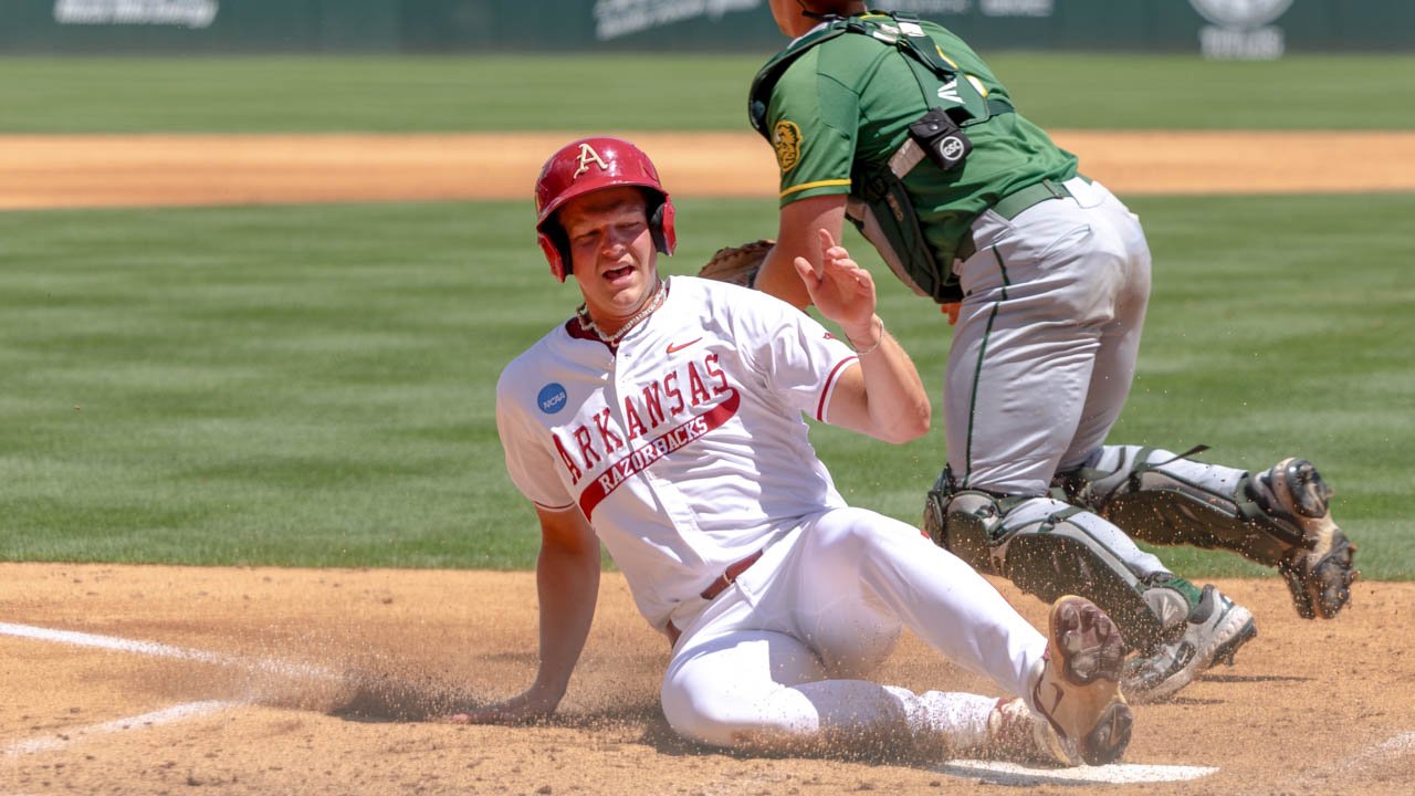 Razorbacks' Cam Kozeal slides across home in an NCAA Regional game against North Dakota State