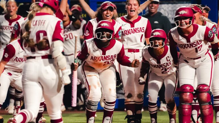 Arkansas softball players wait at home plate to celebrate Kailey Wyckoff's second-inning home run against Nebraska at the Women's College World Series. | Arkansas Communications