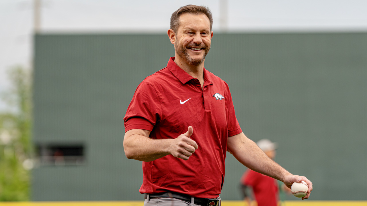 Arkansas Razorbacks coach Ryan Silverfield throwing out the first pitch at a baseball game.