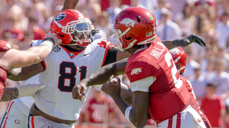Arkansas Razorbacks quarterback AJ Hill delivers a pass while under pressure from a Georgia Bulldogs rusher in a game at Razorback Stadium