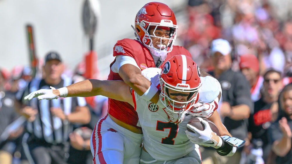 Arkansas Razorbacks defensive back Christian Harrison trying to bring down Georgia Bulldogs tight end Lawson Luckie in game at Razorback Stadium