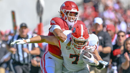 Arkansas Razorbacks defensive back Christian Harrison trying to bring down Georgia Bulldogs tight end Lawson Luckie in game at Razorback Stadium